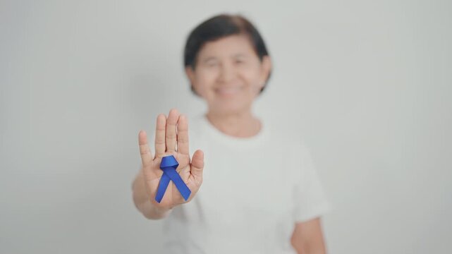 Elderly with dark Blue or Navy blue Ribbon for concept of March Colorectal and Colon Cancer Awareness month, May Arthritis awareness, July Juvenile arthritis and Childhood. Health and world cancer day