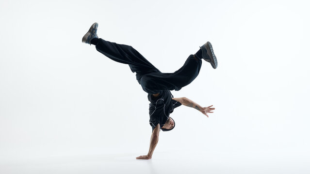 Male breakdancer balancing upside down in controlled freeze pose. Concept of extreme focus, physical discipline, strength training, and street dance mastery.