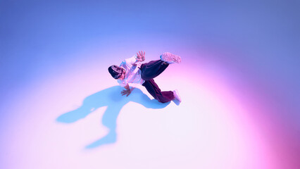 Obraz premium Breakdance dancer performing dynamic floor move with extended leg on gradient background. Concept of street dance expression, athletic performance, body mechanics, and modern lifestyle visuals.