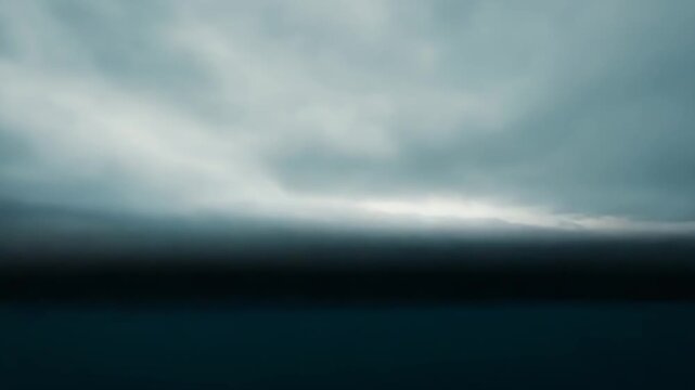 Calm sea reflecting a dramatic grey sky with soft clouds, minimalist expansive seascape evoking quiet, boundless serenity and subtle ripples along the horizon