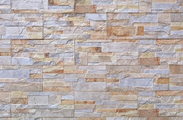 Fototapeta premium Stoneware paneling wall with natural stone bricks effect. Colors are yellow, gray and light brown. Background and texture.