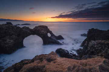 Dramatic coastal landscape of the Snaefellsnes peninsula. Rugged basalt cliffs, moss-covered lava fields, and mountains meeting the ocean in Iceland.