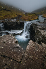 Obraz premium Beautiful Skutafoss waterfall flowing near Hofn. Scenic Icelandic nature with a stream falling over rocky terrain in the East Fjords.