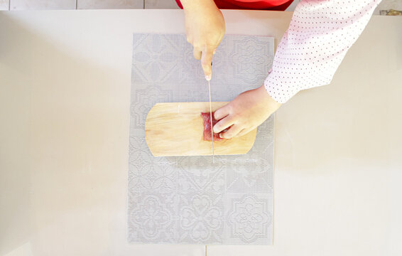 Hands Cutting Raw Beef Meat On Wooden Board