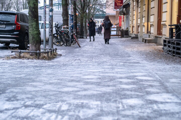 Fototapeta premium Black ice in Berlin. After several freezing cold days and rain last night, the sidewalks in Berlin-Prenzlauer Berg, such as here on Schönhauser Allee, are covered with a thick layer of ice. 