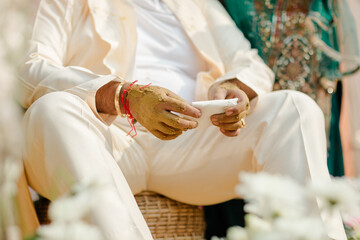 Obraz premium Man With Haldi Paste on Hands Holds a White Cloth During a Traditional Ceremony, Symbolizing Blessings and New Beginnings, Dressed in Cream-Colored Attire