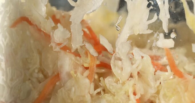 Glass jar with fermented cabbage and carrot, sauerkraut, sauer kraut, healthy vegan crunchy probiotic. Close-up footage on the rotating table.