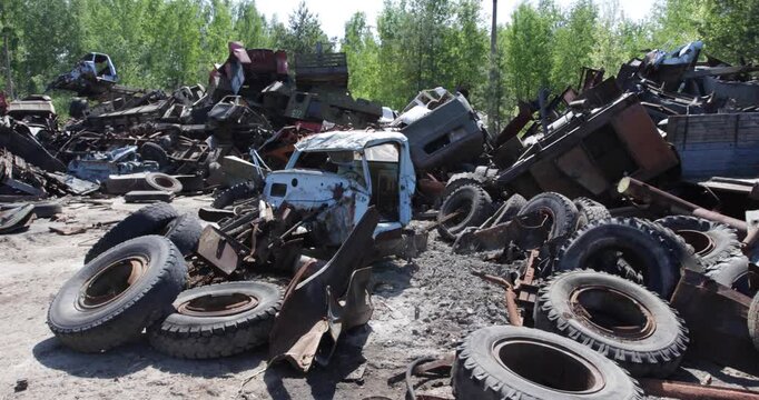 Rassokha Vehicle Graveyard With Rusted Truck Frames And Scattered Tires. Chernobyl Exclusion Zone In Ukraine. panning shot