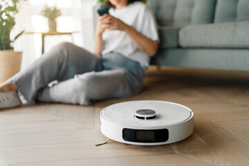 White robotic vacuum cleaner on wooden floor