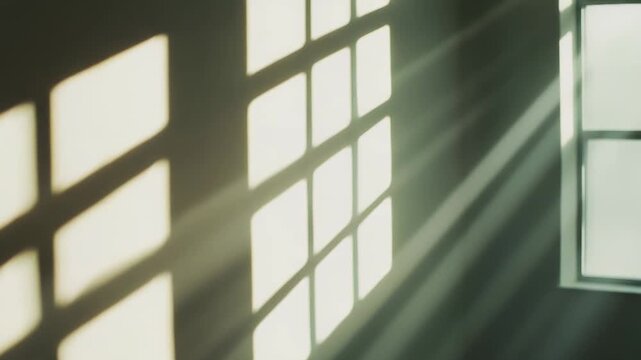 Sunlight beams through a window frame, projecting geometric shadows and creating bright light patterns on an interior wall with a peaceful, calm atmosphere