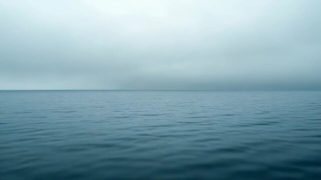 Flat ocean surface reflecting soft daylight, meeting a diffuse light gray sky at a distant horizon, creating a minimalist seascape symbolizing peace, vastness, and calm