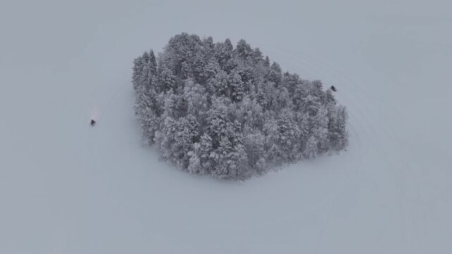 Aerial view of snow-covered trees surrounded by a vast expanse of white, with hints of human activity etched in the snow, Ruka, Pohjois-Pohjanmaa, Finland.