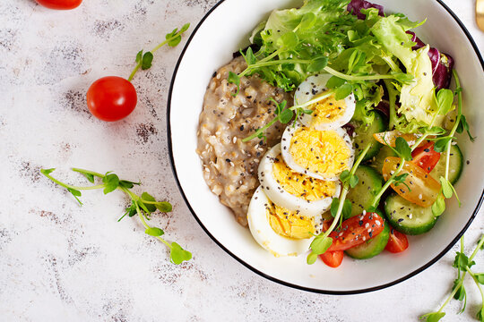 Healthy breakfast Bowl of oatmeal, boiled egg and fresh vegetables. Top view