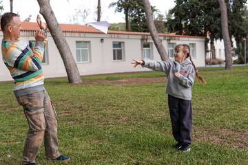 Father and daughter flying paper airplane in park, playful family and childhood