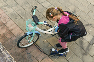 Obraz premium Father and nine year old child pumping wheels of a kid's bicycle outdoors, family activity and childhood