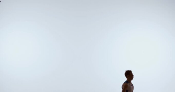 Basketball player jumping upward reaching for falling ball overhead. Concept of reaction training, reflex development, sports coaching, and athletic motion study.
