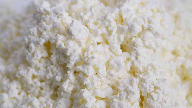 Closeup cottage cheese curds creamy granules, soft crumbly texture with subtle yellow whey, natural dairy tones, macro food detail for recipe packaging and healthy eating visuals