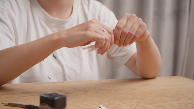 Female hands tearing lined paper into many small pieces on wooden desk. Person destroying written notes due to stress, anger or failure. Clear original sound of paper ripping is included.