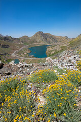 A lake in the mountains, natural scenery, green meadows, snow-capped mountains, blue sky, winter season. Lake views in bloom in spring. Hakkari Cilo Sat Lakes. A lake view in the mountains. 