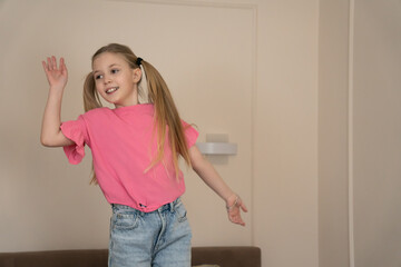 Happy blonde girl with pigtails jumping on a bed in a bright bedroom, wearing pink shirt and jeans, joyful and carefree during playful morning at home, smiling with energy