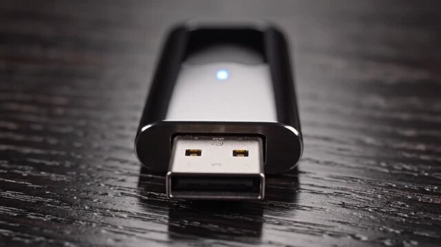 USB flash drive with blue light on wooden table closeup