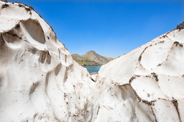 A lake in the mountains, natural scenery, green meadows, snow-capped mountains, blue sky, winter season. Lake views in bloom in spring. Hakkari Cilo Sat Lakes. A lake view in the mountains. 