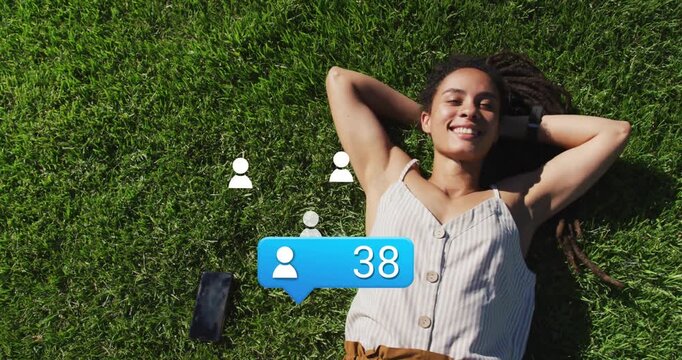 Woman on lawn seeing phone bubble rising, user icons and confetti denoting social media growth