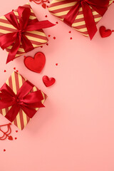 Happy Valentine's Day concept. Flat lay striped gift boxes, hearts and confetti on pastel pink vertical background