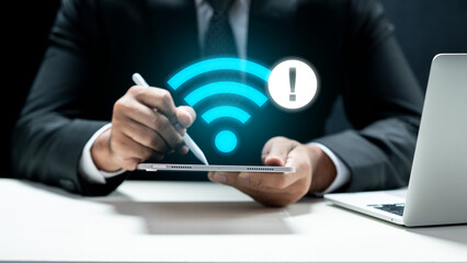 A businessman in a suit holding a tablet that displays a glowing blue Wi-Fi icon with an...