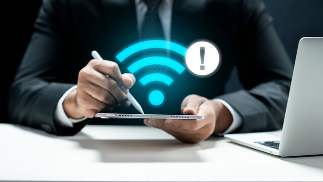 A businessman in a suit holding a tablet that displays a glowing blue Wi-Fi icon with an exclamation mark warning sign, indicating no internet connection or technical connectivity issues