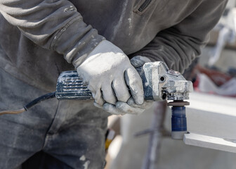 Man drilling holes in ceramic tile with using an angle grinder. Craftmen at work, hands closeup