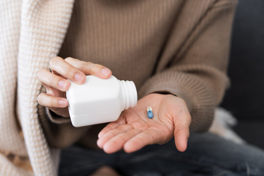 Medication Management. Woman pouring capsule from bottle into hand.