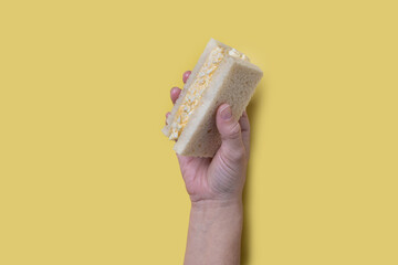 Hand holding Tamago Sando sandwich on yellow background
