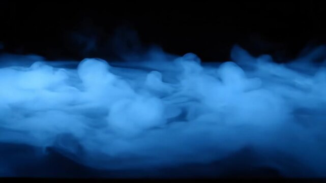 Dense blue smoke from dry ice creeping across a flat surface against a black background