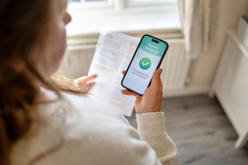 Utility bills successfully paid using mobile banking app on smartphone while holding paper invoice...