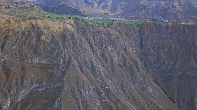 High-altitude drone shot pulled back to reveal more of Cabanaconde while still focusing on Colca Canyon&rsquo;s immense walls, dramatic depth, and the stark contrast between village life and raw nature.