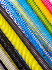 Colorful spirals of plastic binders stacked in rows on a white background during a school supply shopping day