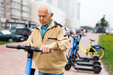 Old man riding down street on electric scooter