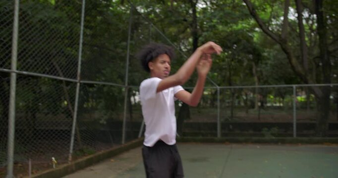 Basketball falling through net after clean shot on outdoor court, followed by African American man grabbing ball and passing to teammate, handheld street game sequence