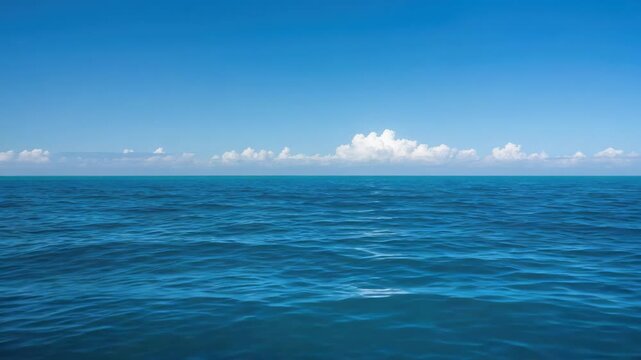Calm blue ocean horizon with gentle waves and scattered clouds over open sea horizon