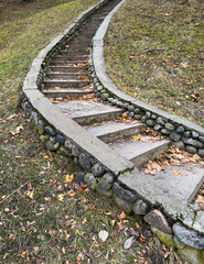 Stone steps forming an old outdoor pathway through green park and garden landscape. Aged staircase