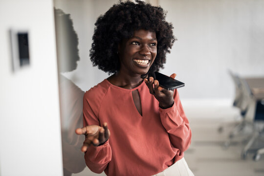 Black woman using smartphone voice command in office