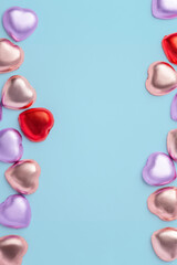 Valentines day and love background, Chocolate hearts with colorful foil wrapped on blue background, top view