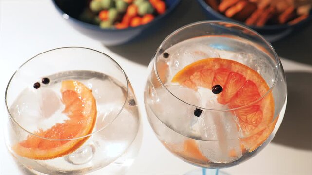 Gin and tonic cocktails, alcoholic drinks with snacks on bar table, with grapefruit and juniper berries