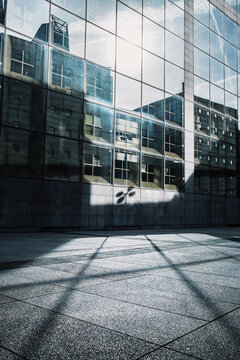 Modern Paris urban architecture glass facade pattern with shadow reflection across plaza creating abstract corporate building background