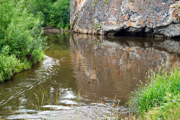 Tall rock formation rising above summer birch and pine forest