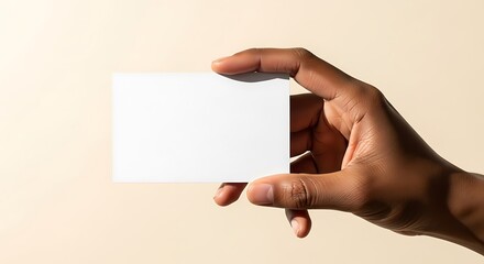 Obraz premium Closeup of African hand holding blank white card on neutral studio background, ideal for branding, mockups, advertising, corporate messaging, contact information, presentations, and marketing designs.