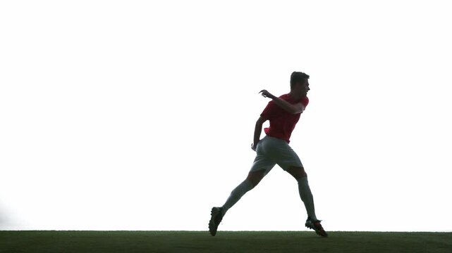 Soccer player running toward ball in dynamic action with intense focus on white background. Concept of football training, speed, anticipation, athletic performance, competition, sports advertising.