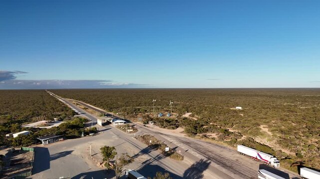 Border Village between South Australia and Western Australia, Eyre Highway, Nullarbor Plain: 4K aerial drone footage of remote roadhouse, boder control, Vehicles, outback highway and vast wilderness