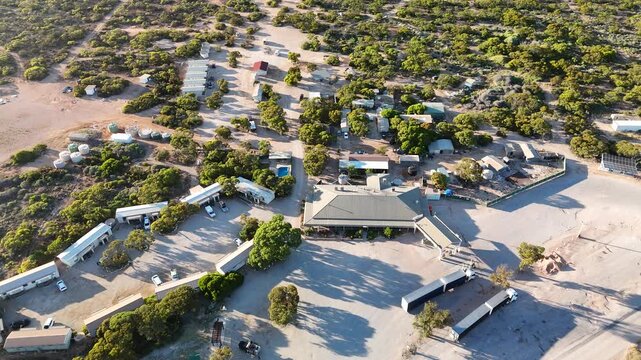 Border Village between South Australia and Western Australia, Eyre Highway, Nullarbor Plain: 4K aerial drone footage of remote roadhouse, boder control, Vehicles, outback highway and vast wilderness